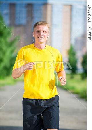 Sporty man jogging in city street park. Outdoor fitness. 19126149