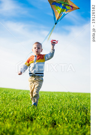 Young boy playing with his kite in a green field. Young boy playing with his kite in a green field. 19126582