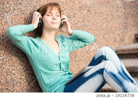 Beautiful young woman student with headphones. Outdoor music girl 19126736