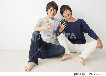 スマホを操作する若い男性と高校生の男の子の写真素材