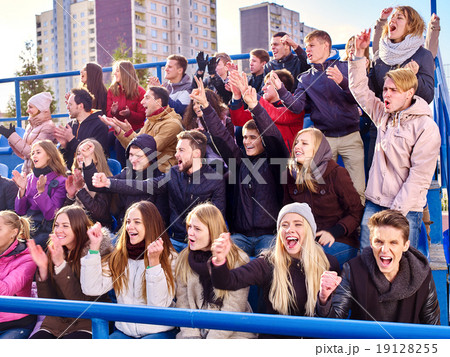 Sport fans clapping and singing on tribunes. 19128255