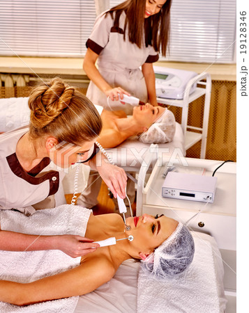 Young woman receiving electric facial massage. 19128346