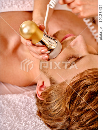 Young woman receiving electric facial massage. 19128434