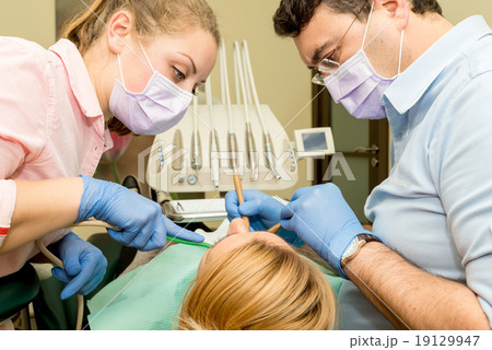 Dentist doing a dental treatment on a patient Dentist doing a dental treatment on a patient 19129947
