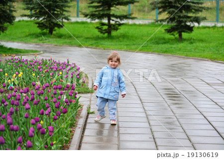 Little girl near the flower beds with tulips 19130619
