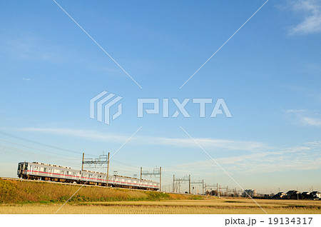 青空をバックに利根川に続く築堤を走る東武電車 19134317