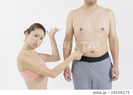 太った男性のお腹の肉をつまむスリムな若い女性の写真素材