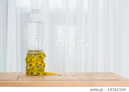 yellow tape measure and a water bottle on wood 19162104