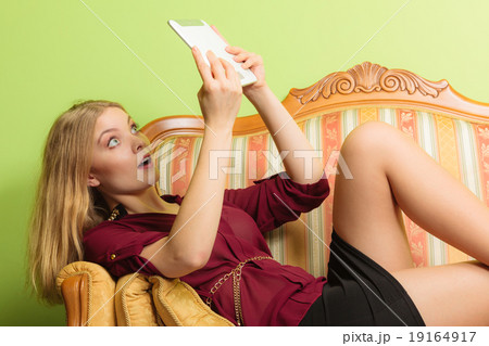 Amazed woman laying on sofa with pc tablet. Amazed woman laying on sofa with pc tablet. 19164917