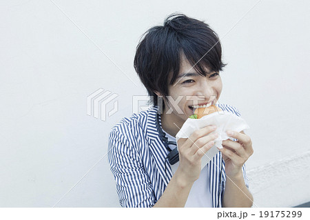 ハンバーガーを食べる２０代男性の写真素材