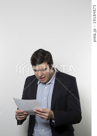 studio shot of angry businessman reading a paper studio shot of angry businessman reading a paper 19184875