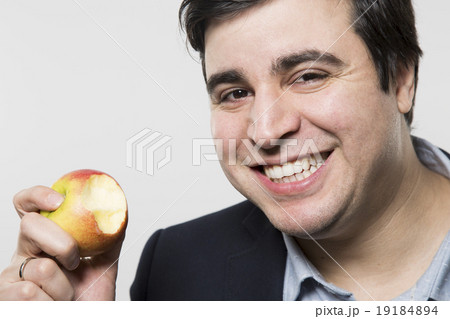 studio shot of happy person eating an apple studio shot of happy person eating an apple 19184894