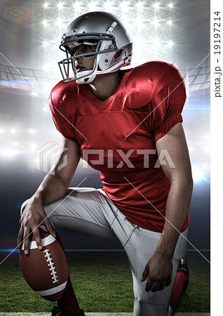 Composite image of sportsman holding american football while kne 19197214