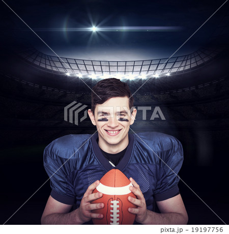 Composite image of smiling american football player holding a ba 19197756