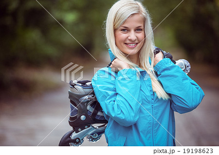 Happy blonde holding inline skates 19198623
