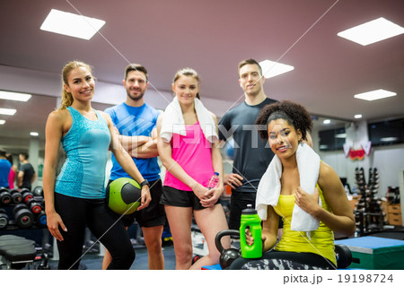 Fit people smiling at camera in weights room 19198724