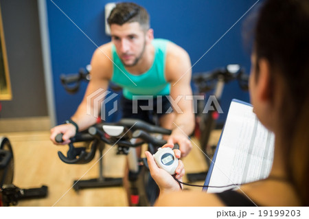 Trainer timing man on exercise bike Trainer timing man on exercise bike 19199203