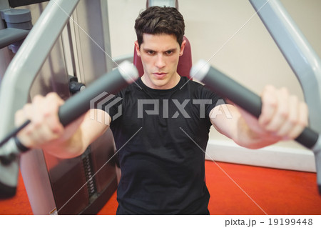 Fit man using weights machine for arms Fit man using weights machine for arms 19199448