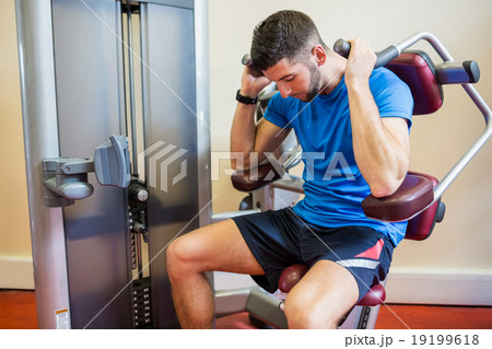 Concentrating man using weights machine 19199618