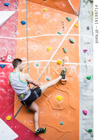 Fit man rock climbing indoors 19199714