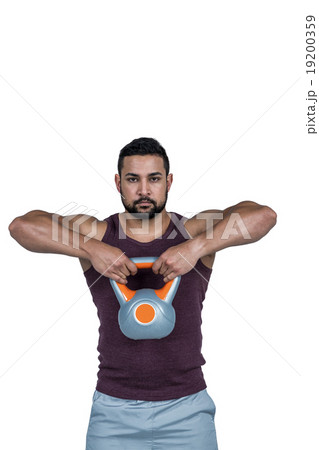 Muscular serious man lifting a kettlebell 19200359