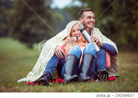 Happy couple sitting under blanket 19200637