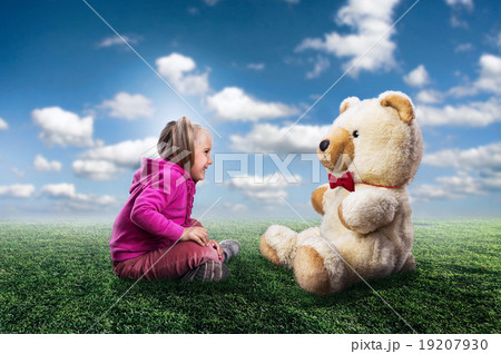 Small cute girl sits and looks at toy bear Small cute girl sits and looks at toy bear 19207930