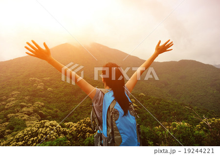 cheering woman hiker open arms at mountain peak 19244221