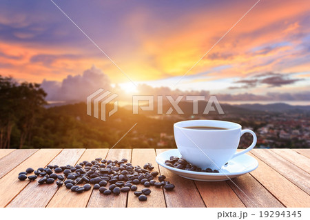 White coffee cup and coffee beans on wood table and view of suns White coffee cup and coffee beans on wood table and view of suns 19294345
