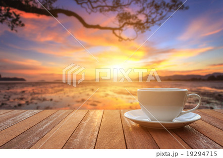 White coffee cup on wood table and view of sunset or sunrise bac White coffee cup on wood table and view of sunset or sunrise bac 19294715