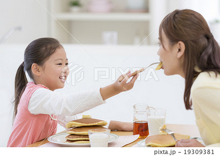 母にパンケーキを食べさせる娘の写真素材