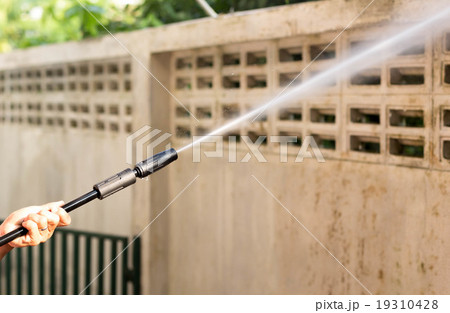 Woman cleaning waill with high pressure water jet Woman cleaning waill with high pressure water jet 19310428