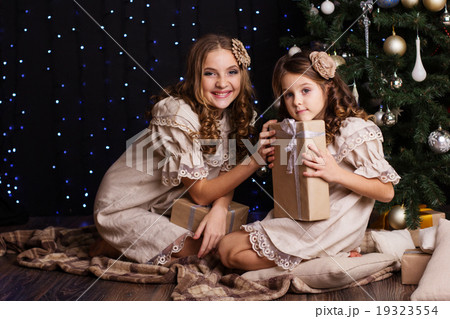 Two girls are sharing gifts near christmas tree 19323554