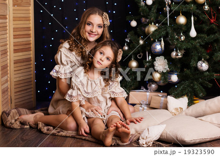 Two sisters with gifts near christmas tree 19323590