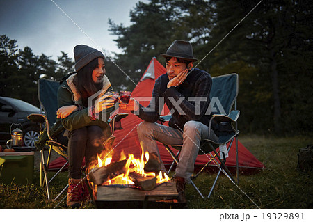 焚き火の前でくつろぐカップル 19329891