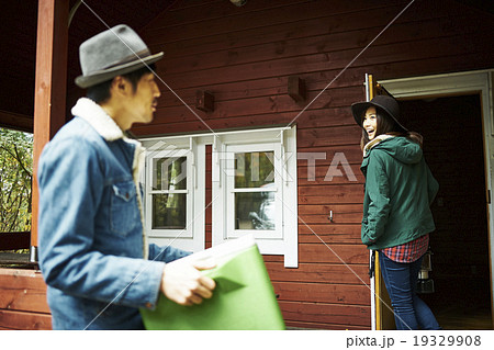 クーラーボックスをロッジに運びこむ男性 19329908