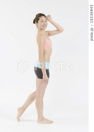 眩しそうに歩くスタイルの良い若い女性 19336845