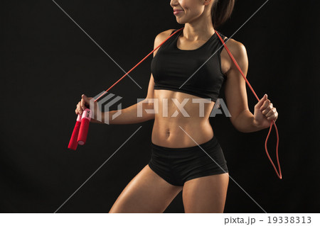 Muscular young woman athlete with a skipping rope 19338313