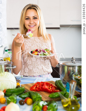 girl standing at kitchen table with plate of salad 19364426