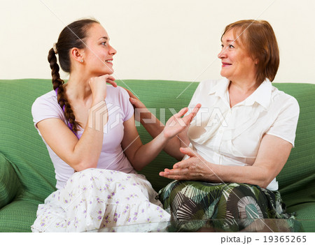 Mature mother and adult daughter gossiping 19365265