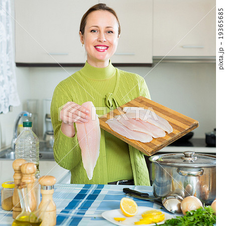 Cheerful female cooking fish Cheerful female cooking fish 19365685