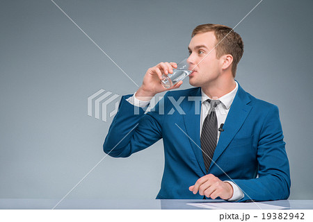 Newsman drinking water at his desk. Newsman drinking water at his desk. 19382942