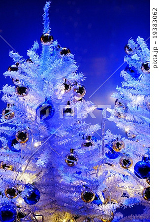 雪の聖夜のイメージ 白いクリスマスツリーとクリスマスボール 青バック縦位置の写真素材
