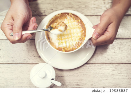 Woman hands with hot cappuccino coffee on a table. 19388687