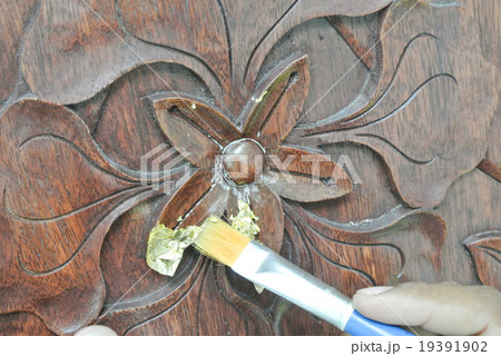 Adding gold leaf skin to the wood carving 19391902