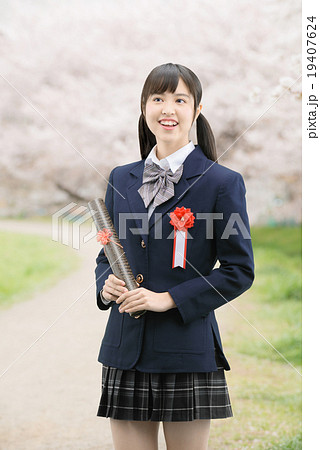 満開の桜並木に立っている制服姿の女子高生の写真素材