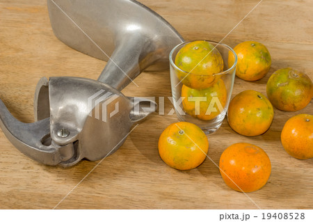 Glass of orange juice and Juicer on wooden table Glass of orange juice and Juicer on wooden table 19408528