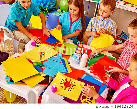 Kids holding colored paper on table in 19412324