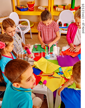 Kids holding colored paper on table in 19412326