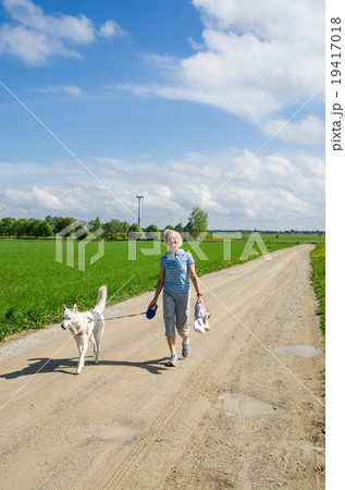 Woman with a dog goes on a country road 19417018